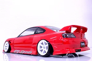 Rear three-quarter view of a red RC drift car body shell, featuring a large rear wing, white wheels, and BN Sports decals.