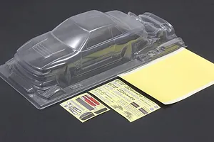 Unpainted clear RC car body shell with separate decal sheets and masking film on a dark surface.