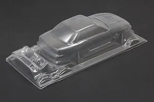 Unpainted clear polycarbonate RC drift car body shell viewed from rear three-quarters on a dark background.