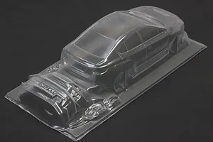 Unpainted clear RC car body shell of a sedan on a dark background.