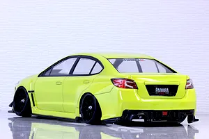 Rear-three-quarter studio view of a yellow Subaru WRX STI RC drift car body shell on black wheels against a white wall.