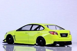 Side-rear view of a bright yellow RC drift car body styled as a Subaru WRX STI mounted on a chassis with black multi-spoke wheels.