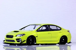 A studio view of a bright yellow Subaru WRX STI RC drift car body shell mounted on a chassis with black wheels.