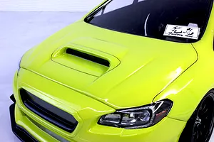 Close-up front angle view of a bright green RC car body featuring a prominent hood scoop and detailed headlights.