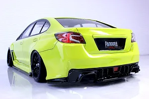 Rear-three-quarter view of a bright yellow RC drift car body shell mounted on a chassis with black wheels against a white studio background.