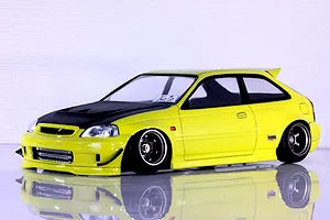 Painted yellow Honda Civic EK9 RC drift car body shell with carbon look bonnet displayed on reflective white surface.