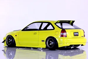 Side-rear profile view of a yellow Honda Civic EK9 Type-R RC drift car body shell on a reflective white studio surface.