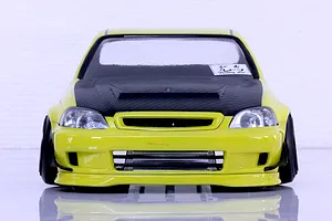 Front view of a yellow RC car body shell featuring a black carbon-fiber-style hood and front bumper details on a white background.