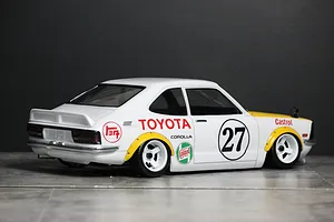 Rear-three-quarter view of a painted white Toyota Corolla Levin TE27 RC body shell with racing decals and number 27.