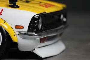 Close-up of the front corner of a painted RC car body shell showing the bumper, grille, and fender.