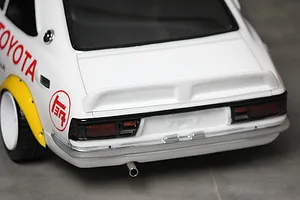 Close-up rear view of a white Toyota Corolla Levin TE27 RC body shell with decals, spoiler, and exhaust tip.