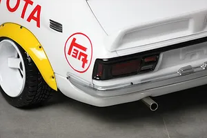 Close-up of the rear quarter of a white RC car body shell, showing a yellow fender flare, Toyota branding, and a chrome bumper.
