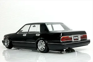 Rear three-quarter view of a black Y31 Cedric sedan RC drift car body shell on a glossy white surface.
