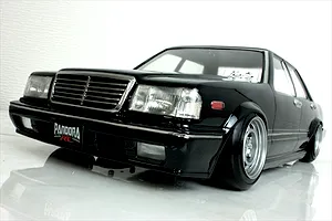 Low angle studio shot of a black Pandora RC Y31 Cedric Sedan body shell mounted on an RC chassis with deep dish wheels.