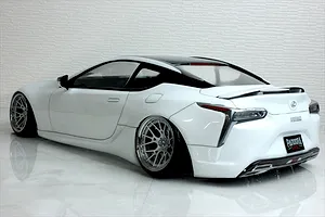 Rear three-quarter view of a white Pandora RC Lexus LC drift body shell on a glossy white surface with a brick textured background.