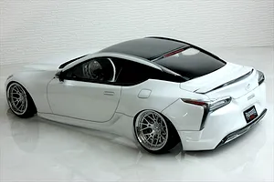 Rear-three-quarter view of a painted white RC drift car body with a black roof and custom wheels.
