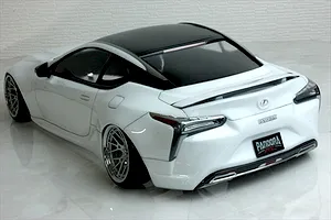 Rear-three-quarter view of a painted white RC drift car body shell modeled after a Lexus with a black roof and custom wheels.