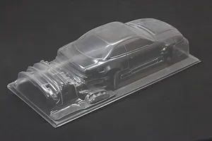 Unpainted clear polycarbonate RC drift car body shell sitting on a dark surface.