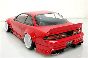 Rear-three-quarter view of a painted red RC drift car body shell mounted on a chassis with white wheels against a white background.