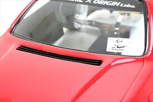 Close-up of the red RC car body bonnet vent and lower windshield area showing decals and chassis components inside.