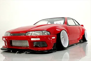 Low angle studio shot of a red S14 Silvia RC drift car body shell with white deep-dish wheels and front intercooler.