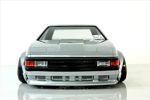 Front view of a silver RC drift car body modeled after a Toyota Celica XX A60 on a reflective white studio surface.