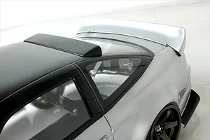 High angle close up of the roof, rear window, and spoiler on a silver and black RC drift car body.