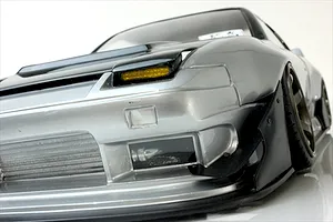 Close-up low-angle view of the front bumper, pop-up headlight, and intercooler on a silver Pandora RC 180SX body shell.