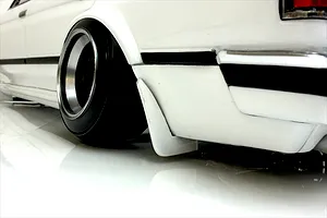 Close-up of the rear quarter section and wheel of a white RC drift car body with a deep dish wheel and mudflap.