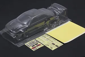 Unpainted clear polycarbonate RC drift car body shell with accessory parts, decal sheets, and mask sheet on a dark background.