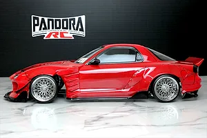 Side profile of a painted red Mazda RX-7 FD3S RC drift car body with BN Sports body kit and chrome mesh wheels.
