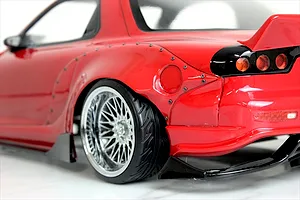 Close-up view of the rear quarter, wheel, and fender flare on a red Mazda RX-7 RC drift car body.