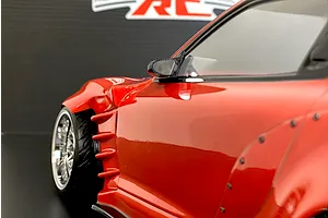 Close-up of a red RC drift car body side profile, highlighting the front fender aero vents, wheel, and mirror.