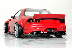 Rear three-quarter view of a red Pandora RC Mazda RX-7 FD3S drift body with wide fenders, rear spoiler, and black diffuser on a reflective surface.