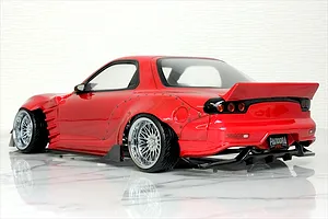 Rear three-quarter view of a red RC drift car body shell, specifically a Mazda RX-7 FD3S with wide fenders and a ducktail spoiler.