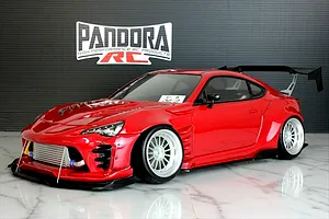 Red Pandora RC Toyota 86 BN Sports drift body shell mounted on a chassis with custom wheels and a large rear wing.