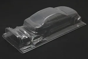 Unpainted clear polycarbonate RC car body shell with additional bumper parts on a dark background.