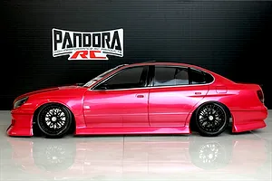 Side profile of a painted red RC drift car body shell on a gloss floor with Pandora RC logo in the background.