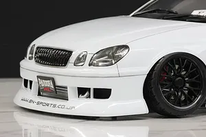 Close-up of the front end of a white RC drift car body showing the bumper, grille, headlight, and black wheel.