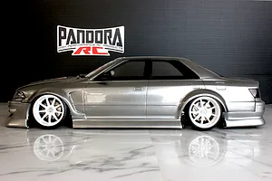 Side profile of a silver RC drift car body shell with white wheels displayed on a glossy marble surface.