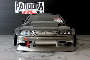 Front view of a dark grey Pandora RC Toyota Mark 2 body shell with a front mount intercooler and red tow strap on a marble surface.