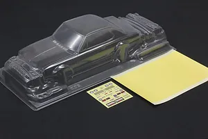 Unpainted clear RC car body shell with a sticker sheet and masking sheet on a black background.