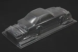 Unpainted clear polycarbonate RC car body shell for a KPGC10 Skyline HT 2000GT-R on a dark surface.