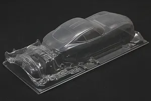 Unpainted clear polycarbonate RC car body shell for a Toyota 2000GT with separate molded detail parts on a dark background.