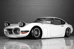Painted white Toyota 2000GT RC drift and touring body shell mounted on a chassis with pop-up headlights.