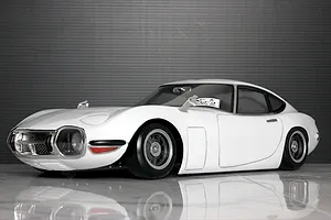 Studio shot of a white Pandora RC Toyota 2000GT body shell mounted on an RC chassis against a dark grey background.