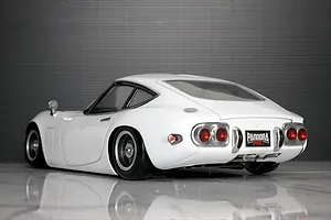 Rear three-quarter view of a white Pandora RC Toyota 2000GT body shell on a reflective surface.