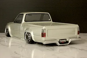 Rear three-quarter view of a custom silver RC drift truck body shell on a marble surface.