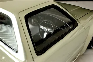 Close-up view of the interior cabin and steering wheel through the driver side window of a silver Toyota Hilux RN80 RC body shell.
