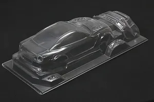 Unpainted clear polycarbonate RC car body shell for an R35 GT-R with additional parts on a black background.
